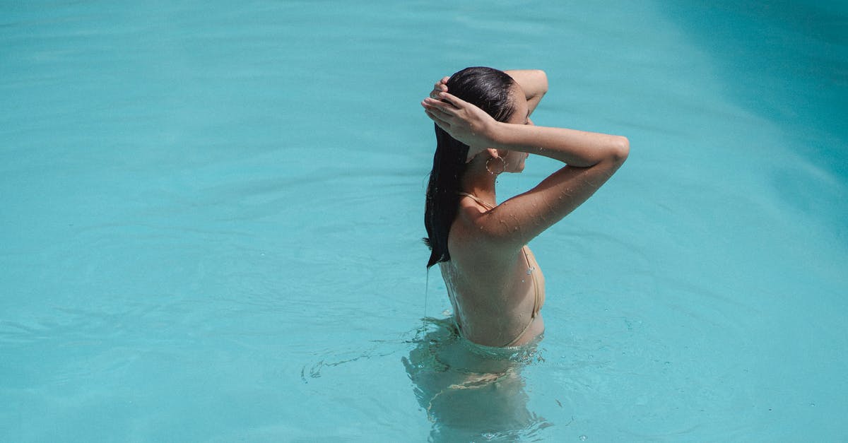 Price limits for self-arranged hotel after flight cancellation - Sensual young ethnic female touching hair while swimming in pool