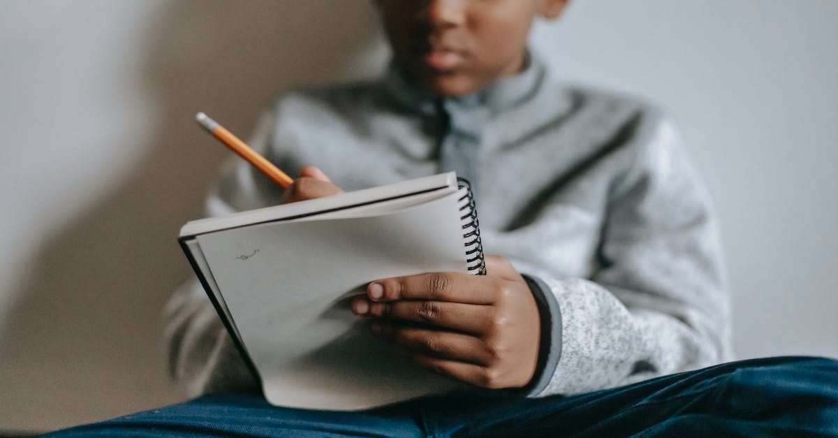 Primary occupation for the US visa - student or professional? - Low angle of crop smart ethnic boy sitting on floor with notepad and writing