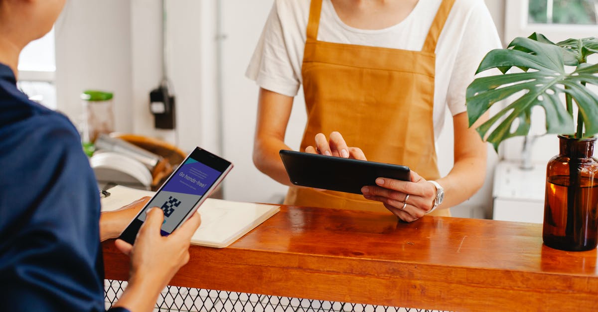 Printed Ryanair boarding pass has no QR code - Crop anonymous female employee with application on cellphone screen interacting with partner using tablet at counter in cafeteria