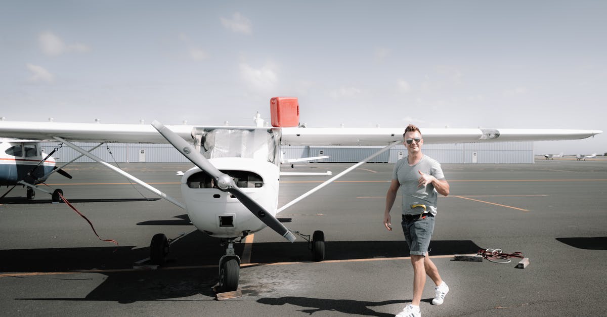 Private charter flight [closed] - Full body young happy male wearing casual clothes strolling near modern propeller jet parked on airfield on clear summer day and showing thumb up