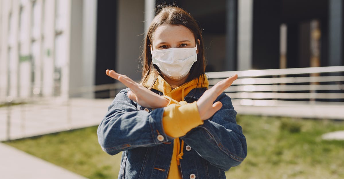 Problem at filling self declaration COVID – 19 Italy - Girl in medical mask showing stop looking at camera