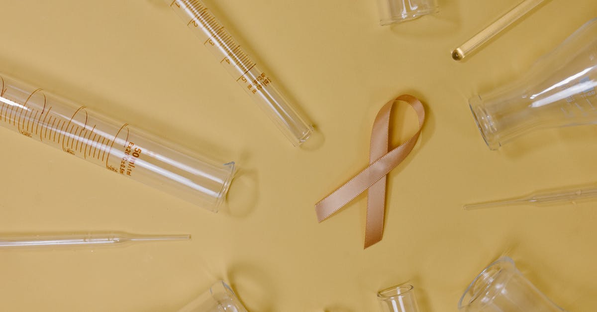 Problems associated with booking flights inside another set of flights? - Top view of pink ribbon representing cancer placed on yellow background among glass test tubes and flasks in light studio