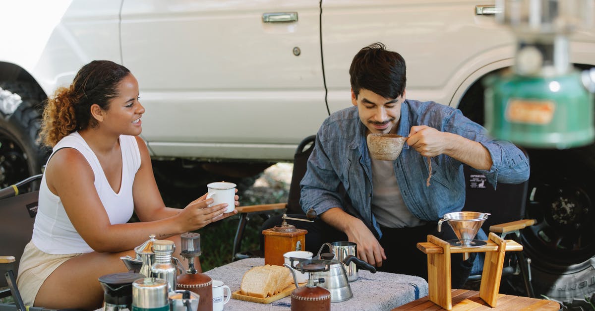 Processing a visa application with a past expected travel date - Positive diverse couple drinking delicious pour over coffee in campsite