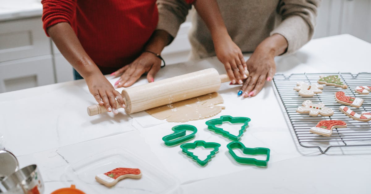 Processing time of a working holiday visa in New Zealand - From above of crop unrecognizable ethnic child rolling out dough near parent while preparing gingerbread cookies in kitchen