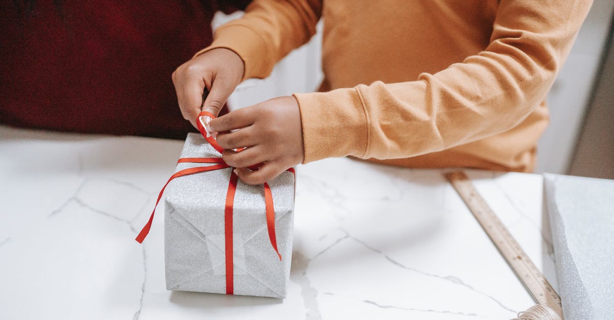 Processing time of a working holiday visa in New Zealand - Crop ethnic child tying ribbon on gift box at home