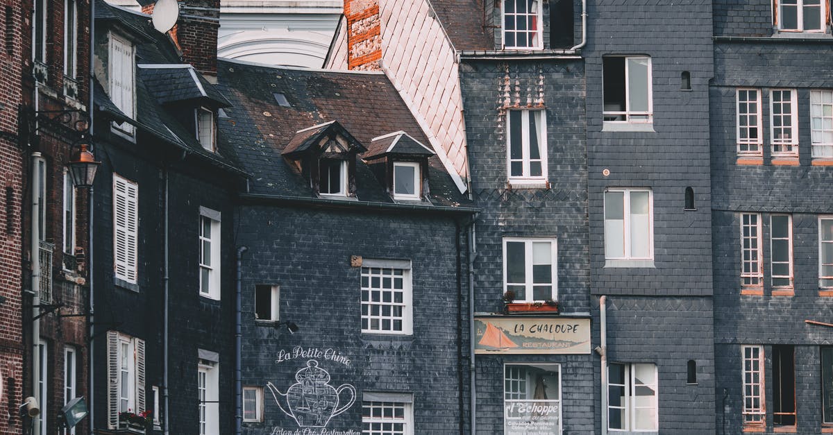 Proof of accommodation for France (travelling from India) [closed] - Exterior of old black brick residential houses with mansard windows located in Honfleur city on sunny day