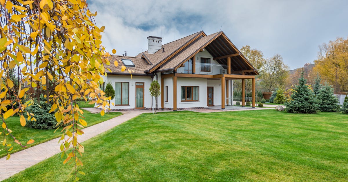 Proof of accommodation in UK for Schengen visa - Exterior of residential suburban cottage with balcony surrounded with lush green plants and trees