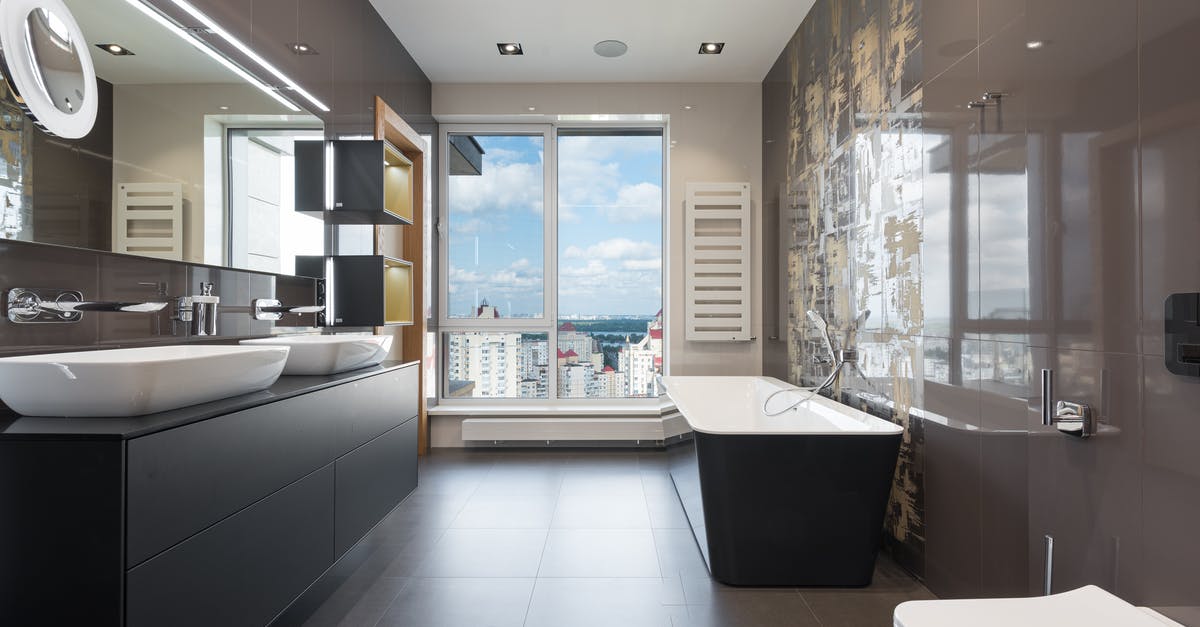 Proper technique to wash laundry in hotel sink? - Wooden furniture with bathtub and ceramic sinks and toilet bowl in contemporary master bathroom with big windows in daylight