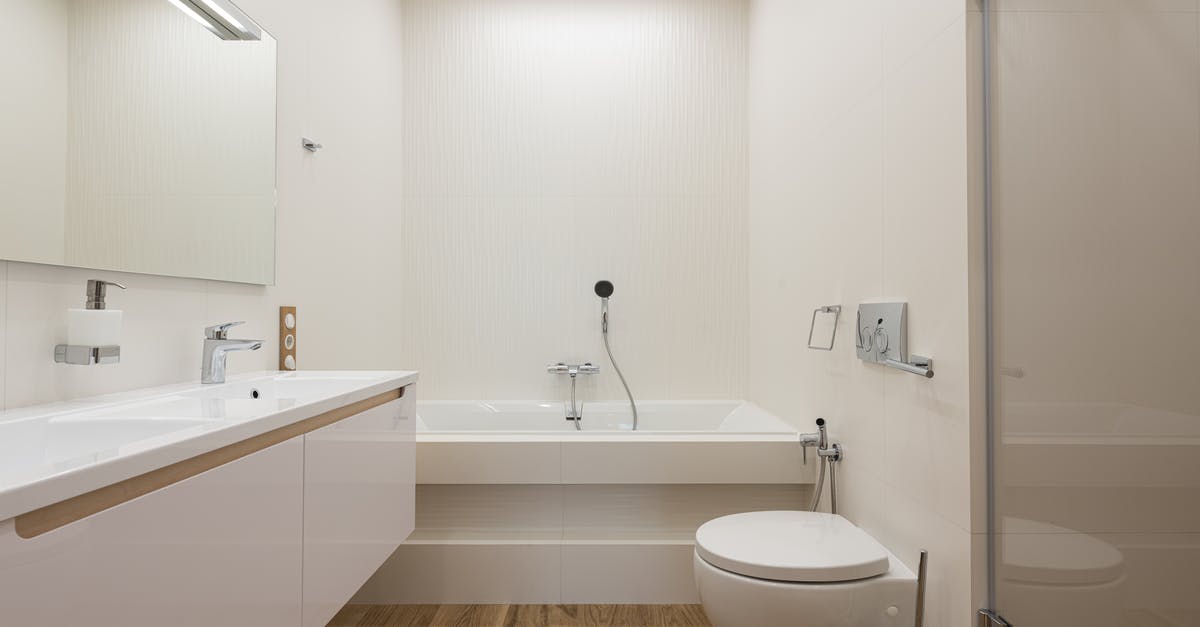 Proper technique to wash laundry in hotel sink? - Bathtub and shower cabin in light bathroom with white furniture and tiled walls