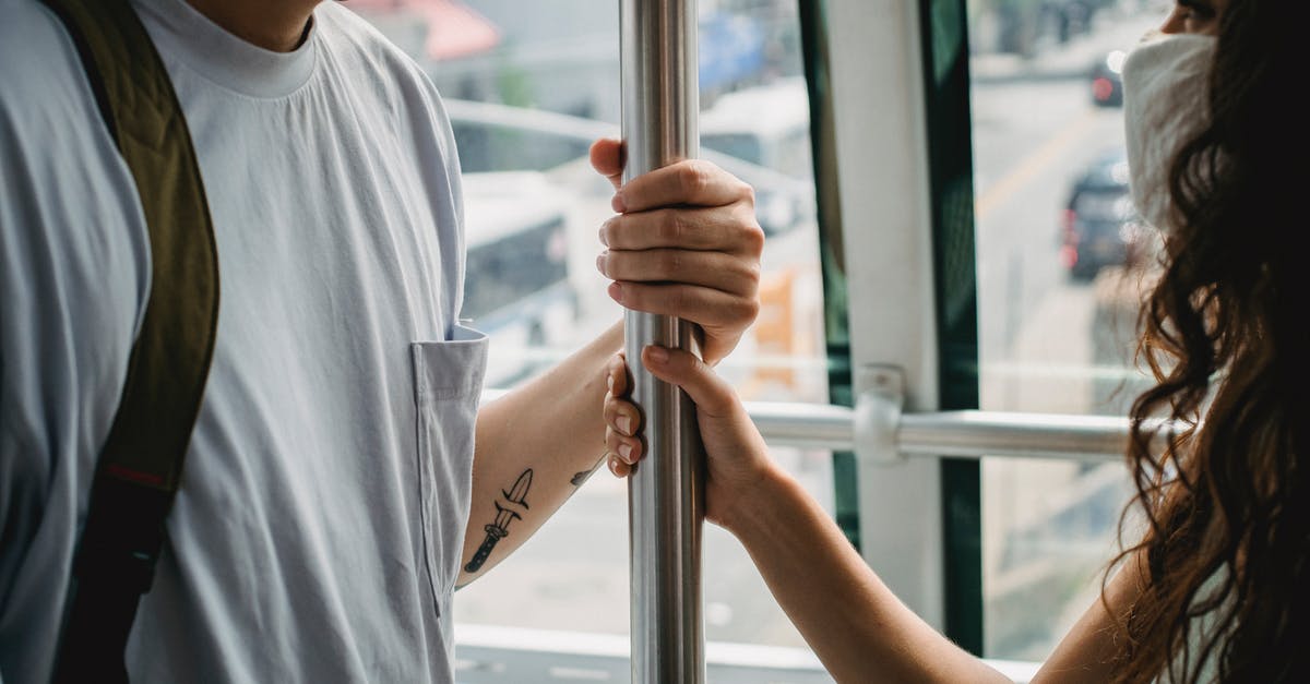 Pros/Cons for horizontal or vertical cabin trollies [closed] - Crop couple in masks riding ropeway cabin in urban city