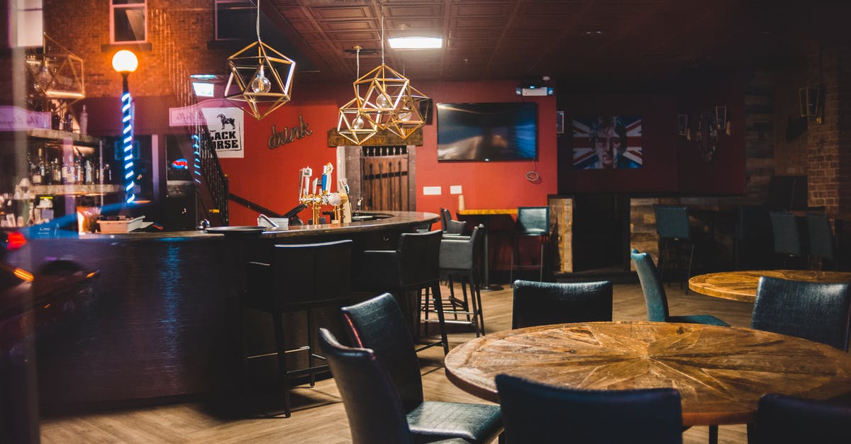 Pub quizzes in Bath, UK - Round wooden tables and leather chairs in cozy bar with counter decorated with creative lamps