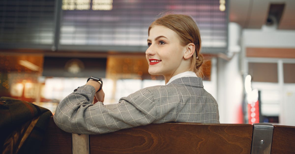 Public transport from/to Rhodes Airport - Side view of positive female manager waiting for flight on wooden seat in airport