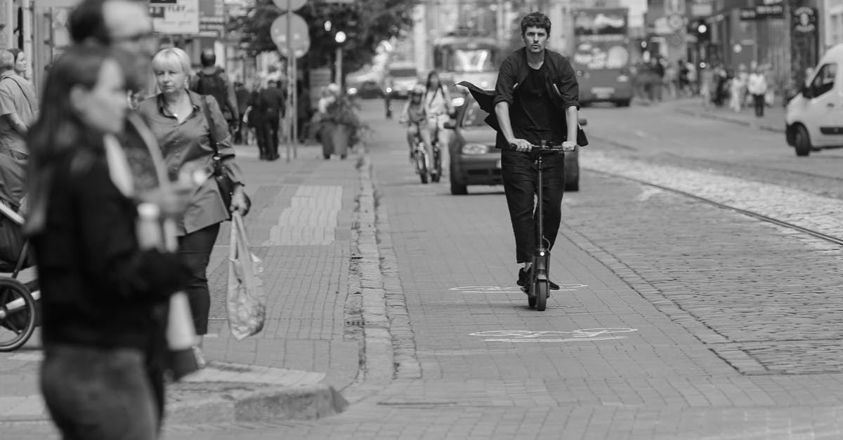 Public transport (Lynx buses) Orlando, FL - "fixed route" pass - Black and white passers by walking and riding scooter along busy city road with moving cars on summer day