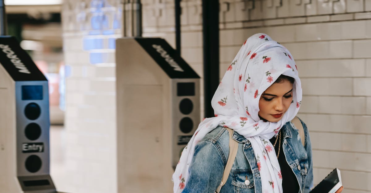 Public Transport planner for Hanover (Hannover)? - Calm Muslim woman with copybook wearing floral headscarf wearing jeans jacket with backpack entering subway station through automatic turnstile