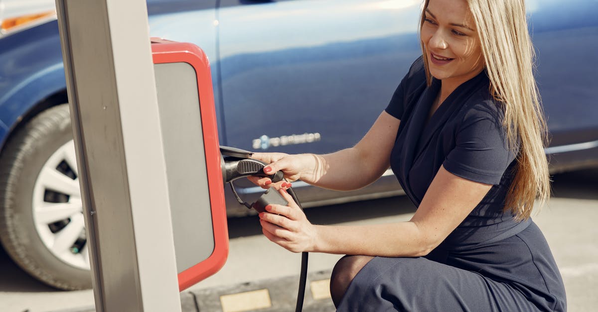 Publicly-accessible electric sockets in Munich to charge dead devices? - Side view of positive female in casual dress sitting near station on street charging electric vehicle for continuation trip