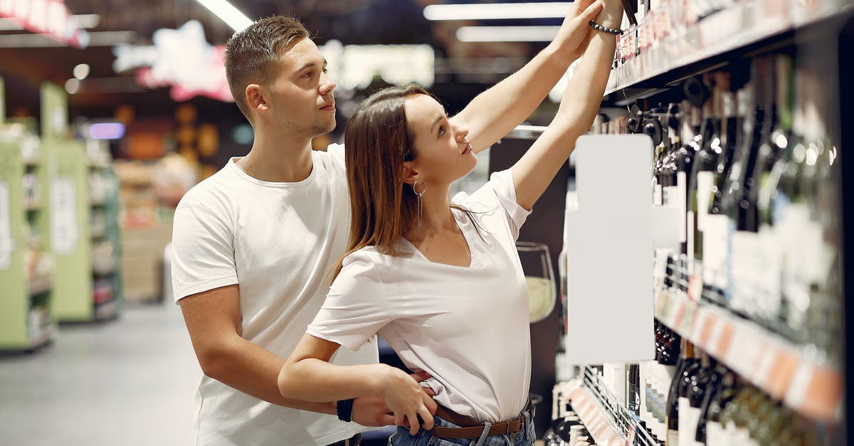 Purchasing a bottle of wine after security over 100 ml - Young couple choosing food in grocery store