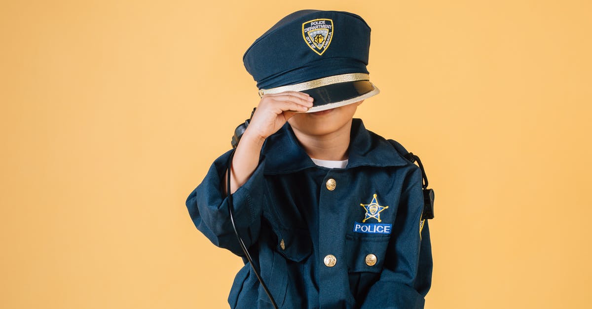 Purpose of the 'Witches' Hats' on the A13 in London - Unrecognizable child in police uniform standing in studio with transceiver in hand and pulling cap over face on yellow background