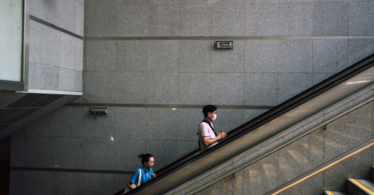 Quarantine Rule in New York - Anonymous man and woman on escalator during COVID 19 pandemic