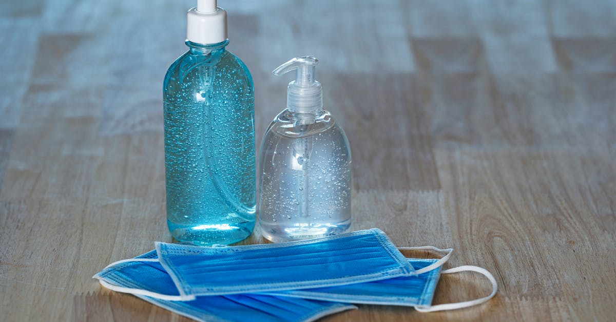 Quarantine Rule in New York - From above of transparent bottles with bubbled antiseptic liquid soap and gel near medical masks on table