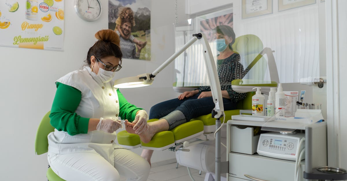 Quarantining process in JFK/NYC? - Concentrated professional beauty master in protective mask and gloves doing pedicure in modern salon