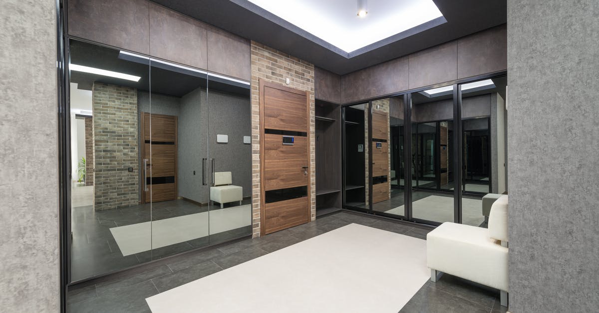 Queenstown, New Zealand private transfers - White pouf placed at gray wall in spacious hallway of stylish light apartment with wooden door and mirrors with reflection