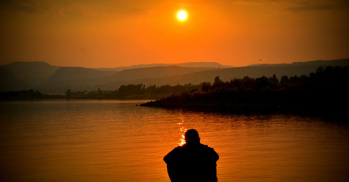 Question about water bottles - Silhouette of Person Sitting Beside Body of Water