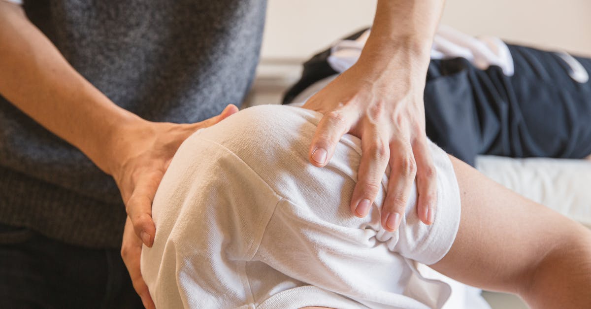 Quitting job to visit my UK boyfriend for longer - Crop anonymous medical specialist rubbing shoulders of male client lying on couch in medical salon