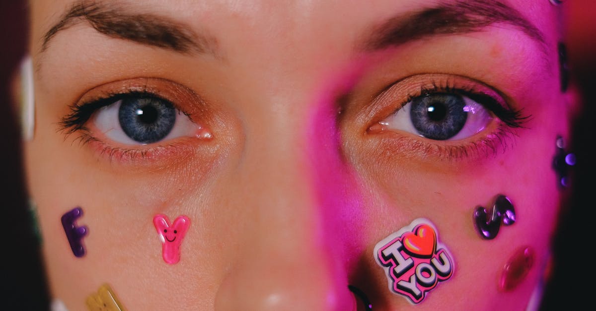 "You look tired!" In which countries is this a compliment? [closed] - Crop calm female with nose piercing and letter stickers on face standing on dark background and looking at camera