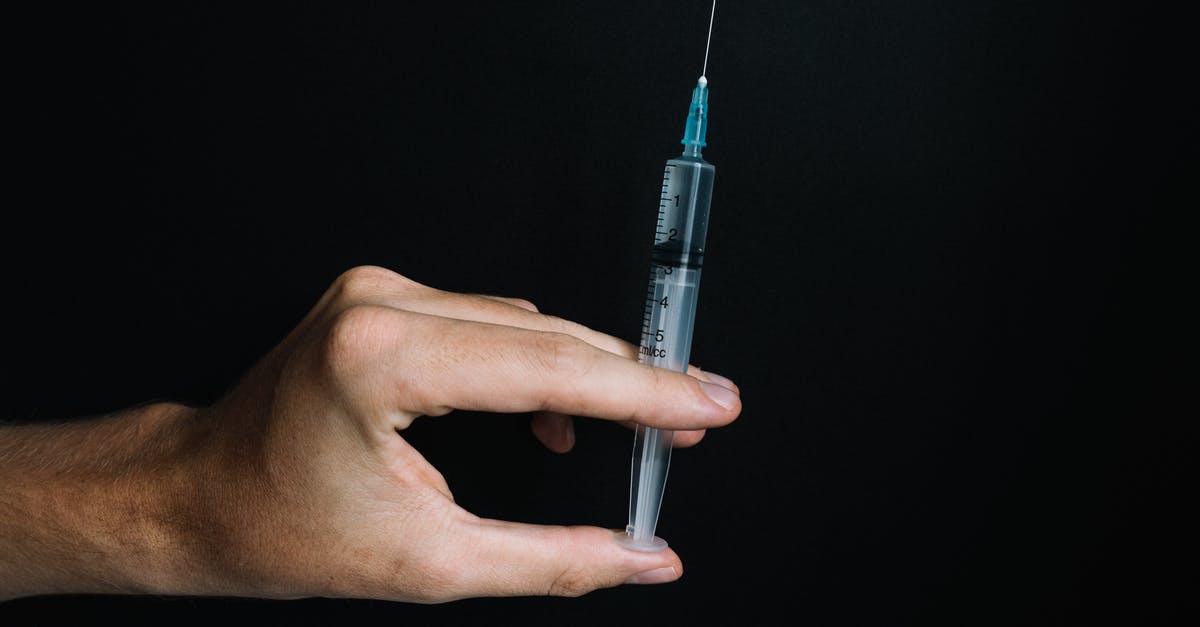 Rabies vaccine booster dose in Indonesia? - Person Holding a Syringe on Black Background