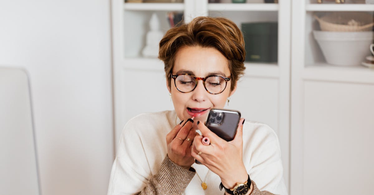 Re-applying after a refused visa application - Woman putting on lipstick using smartphone front camera