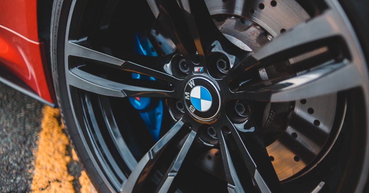 Red triangle, yellow jackets, etc. for rental cars in France - From above modern red auto wheel metal rim with shiny lug nuts on asphalt road with marking line