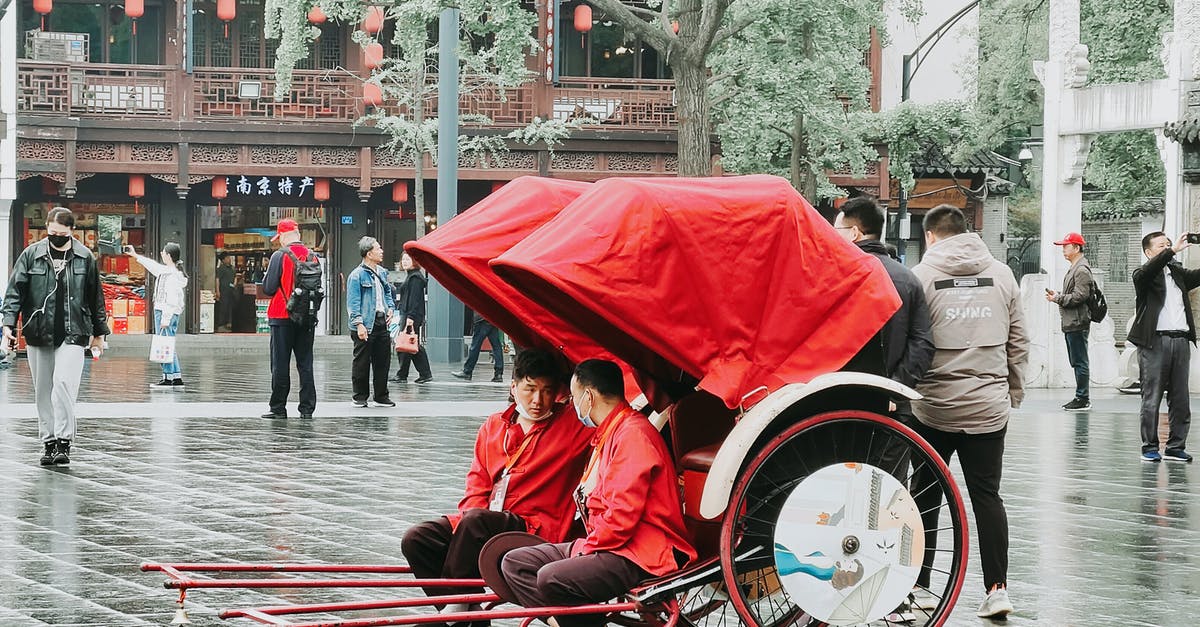 Re-entering China on a tourist visa - Man in Red Jacket Sitting on Red and White Stroller