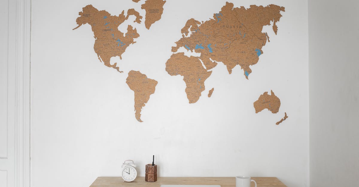 Registration during Russian World Cup - Alarm clock near pen container with cup and laptop on table placed near silhouettes of world map on wall