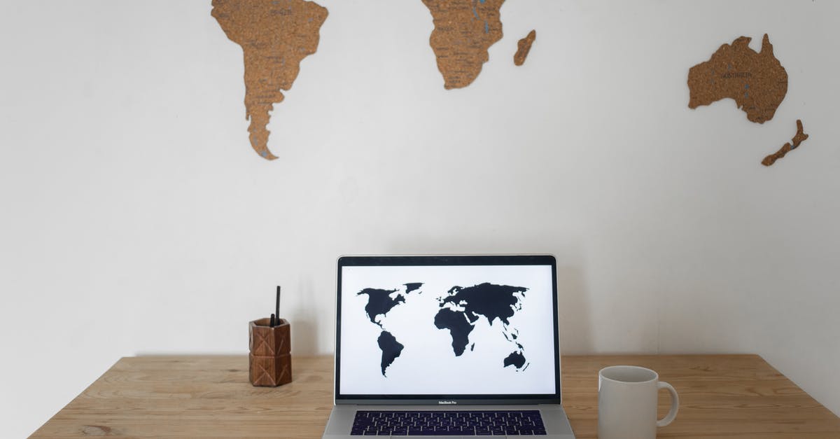 Registration during Russian World Cup - Black world map on laptop screen and ceramic cup with pen container placed on table against silhouettes of continents