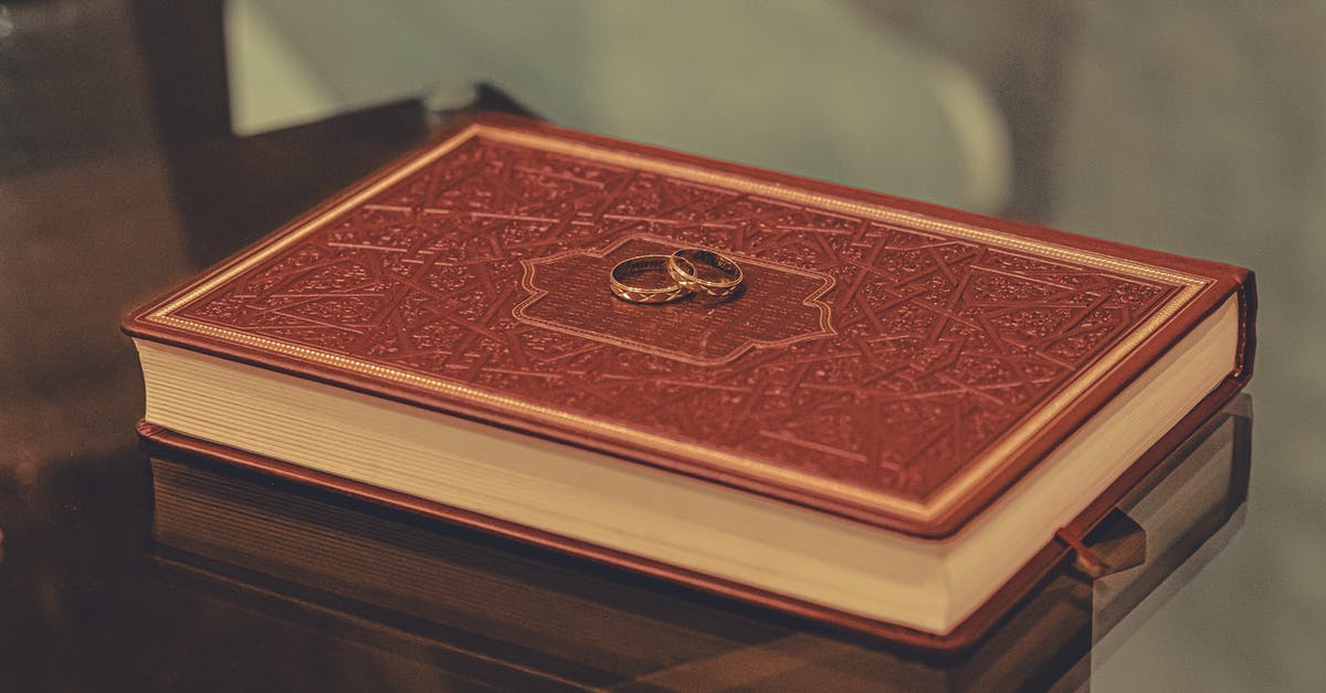 Religious wedding after civil wedding - Composition of golden rings placed on red ornamental book placed on glass table