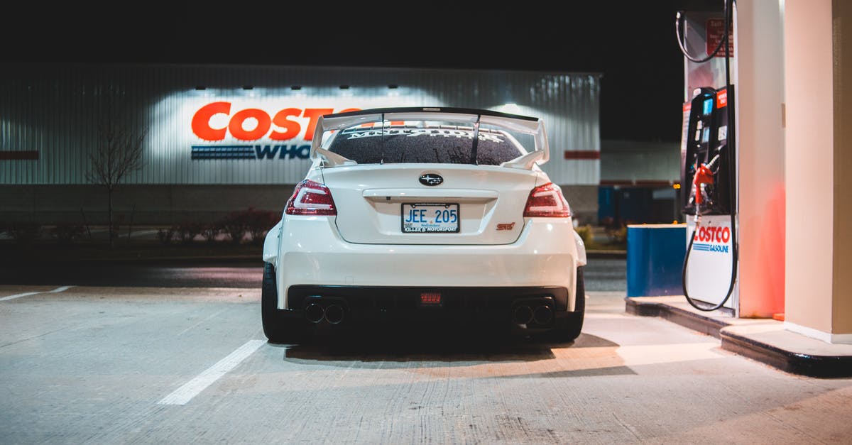 Rented car in Switzerland: fuel and gas station - Contemporary white car parked near pump on fuel station at night in city