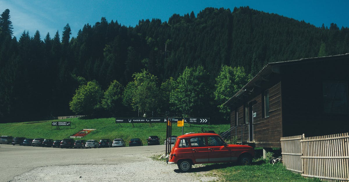 Renting a car from Milan to Switzerland - Red 5-door Hatchback Near the Brown Wooden House in Daytime