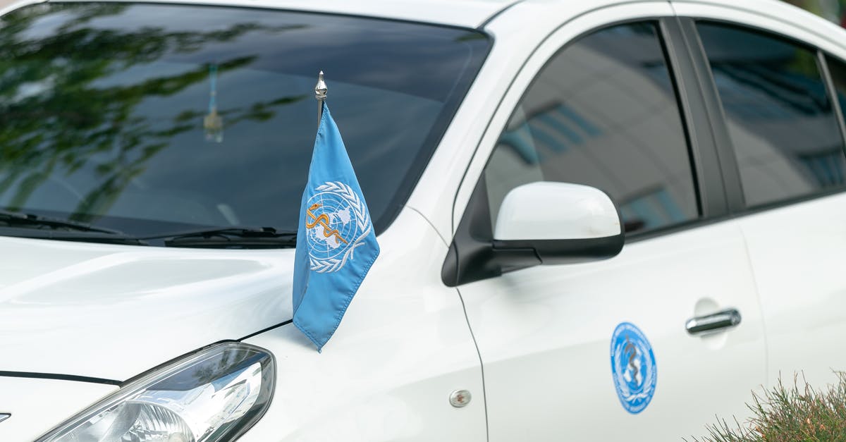 Renting a car from Milan to Switzerland - Contemporary white car decorated with blue World Health Organization flag and sticker parked on street