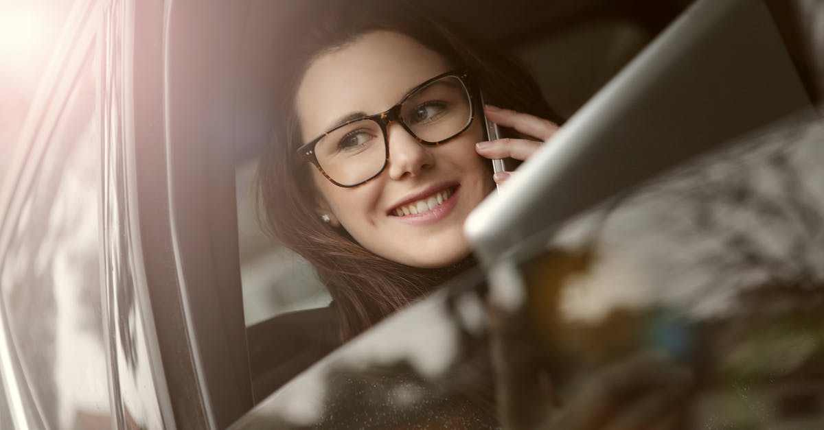 Renting a car from private persons in California - Female in glasses with tablet talking on smartphone while sitting in car with opened window