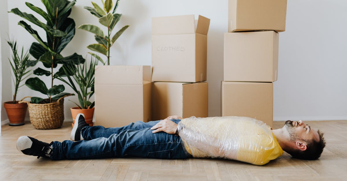 Renting a flat in Montenegro [closed] - Full body side view unemotional male wearing casual outfit lying on floor with upper body tied up with tape and tired after packing belongings into carton boxes