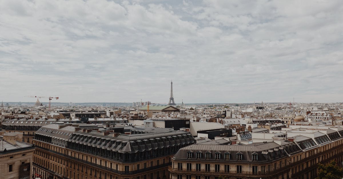 renting/letting/hire/location a scooter in Paris France (from US) - High angle of aged buildings of old Paris with Eiffel Tower at distance under cloudy sky