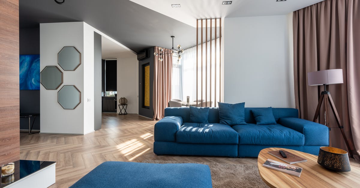 Repercussions of denied entry on Schengen zone without a visa - Interior of spacious flat with blue sofa and pouf near wooden table placed on carpet near wall with stylish decorations