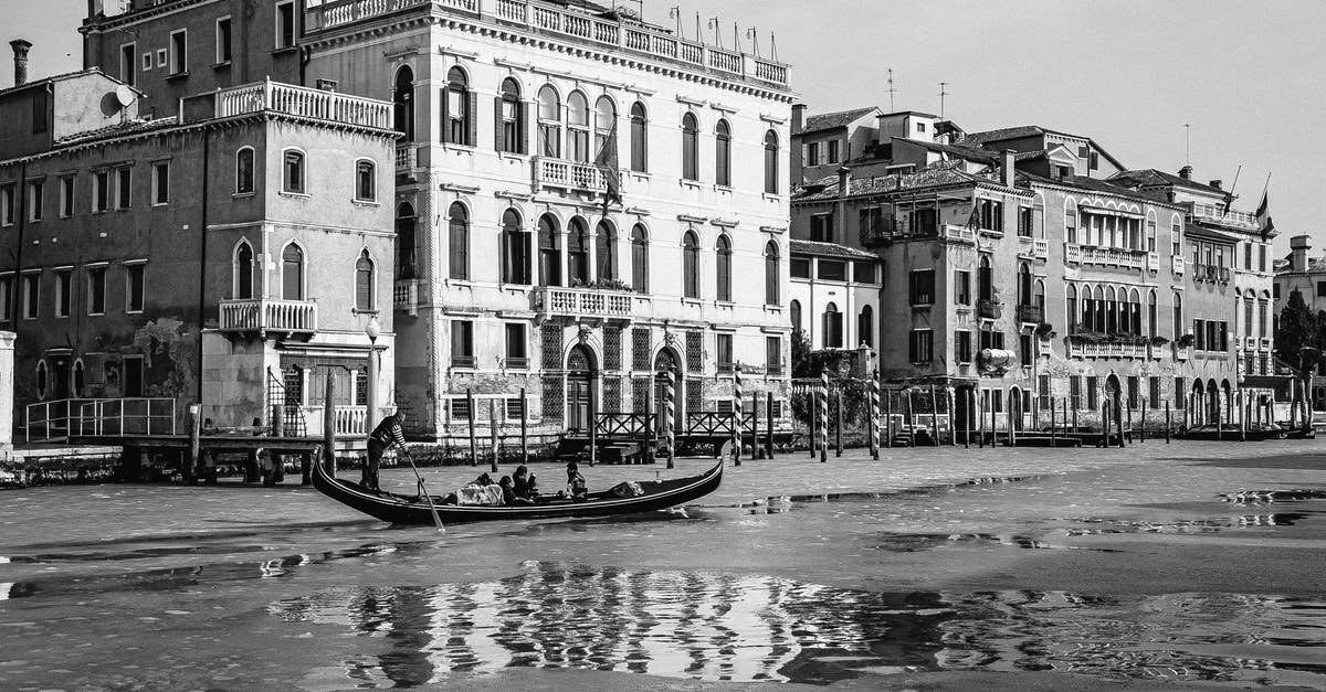 Requirements when transiting Italy - Grayscale Photo of People Riding on Boat on River Near Buildings