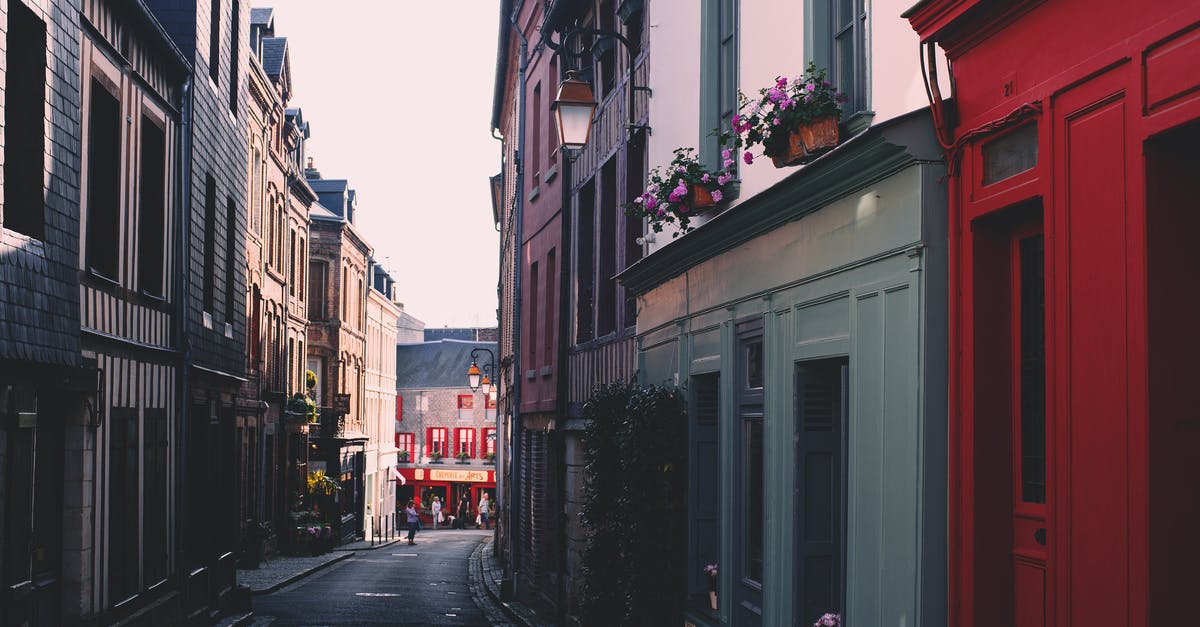 Resource to find regular flights between given cities - Paved road on narrow alley between residential building with colorful facade and windows located in town on street against cloudless sky