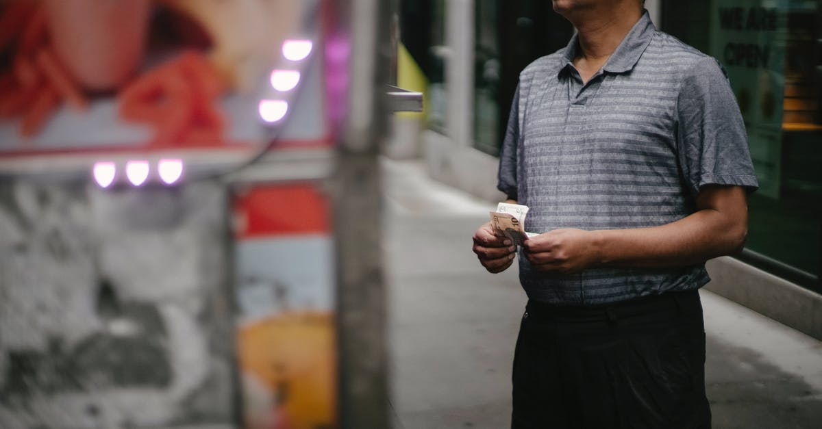 Restaurants in Leipzig, Germany that offer local food - Crop male customer with banknotes in eyeglasses making choice at food truck on street