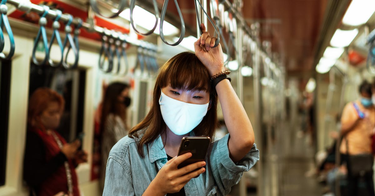 Retaining access to email when traveling - Woman Wearing a Face Mask on the Subway and Using her Smartphone