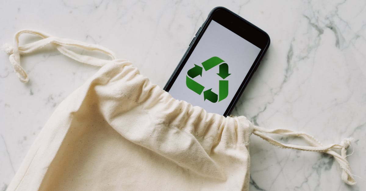 Reusing phone from 2007 - Top view of plain white cotton sack and smartphone with green recycle emblem composed on marble surface