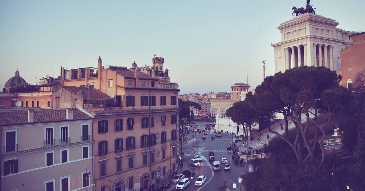 Road trip in Europe while German resident permit is pending - Various cars driving on asphalt road near aged residential buildings and famous Victor Emmanuel II Monument against cloudless blue sky in Rome