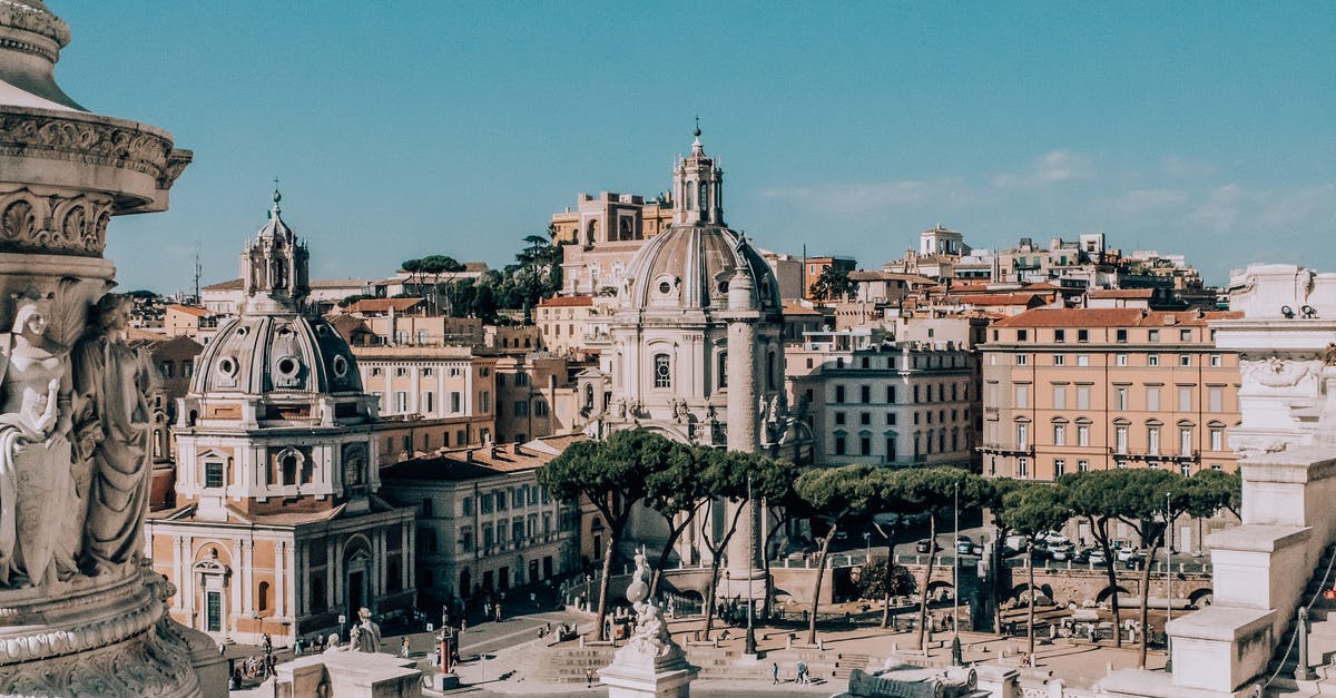 Roaming charges from country to country in Europe - From above of aged masonry churches near houses and statues under blue cloudy sky in Italy