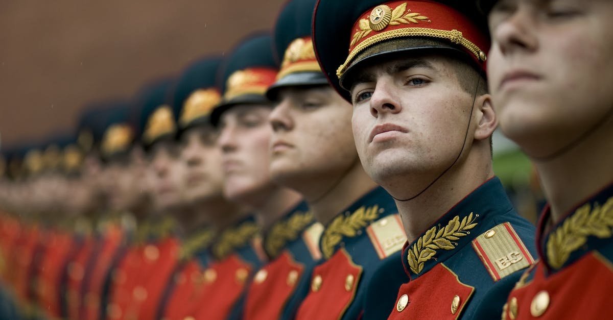 Russians leaving Russia (during covid times) - Men in Black and Red Cade Hats and Military Uniform